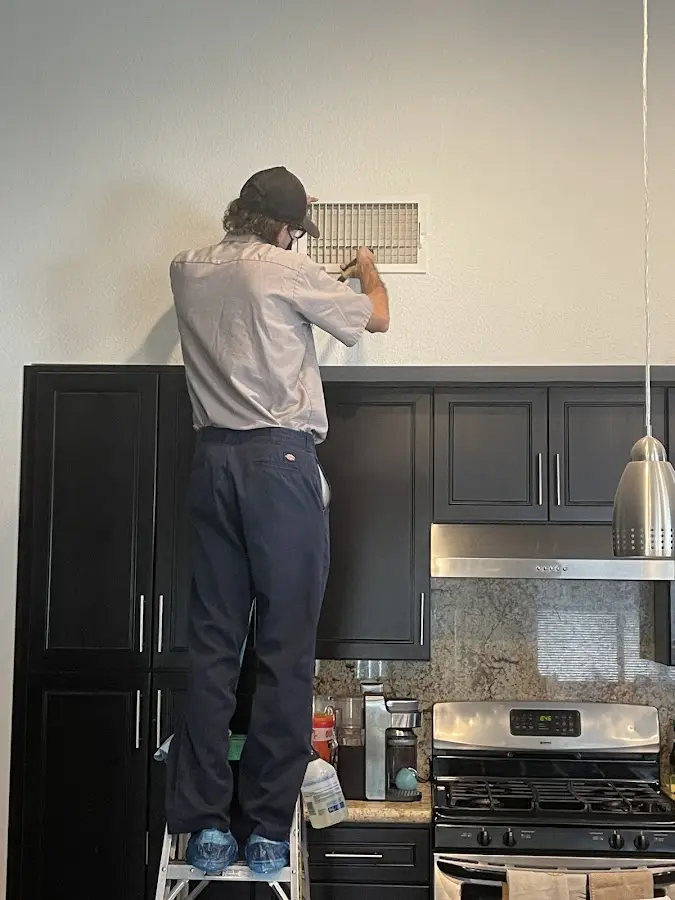 Technician inspecting an air vent during HVAC service in Duarte